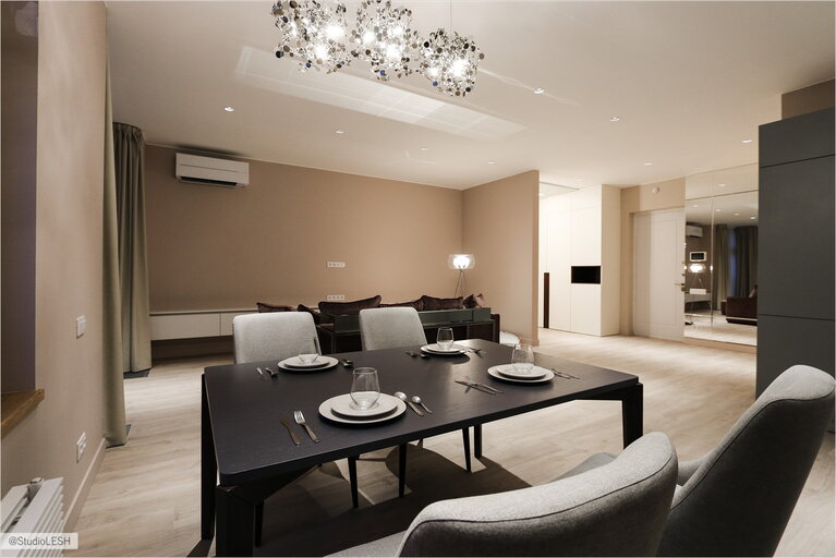 Обеденная зона в просторной кухне-гостиной с дизайнерской люстрой