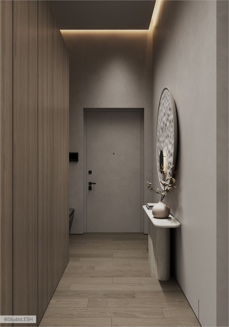 Интерьер современного коридора с серыми стенами, деревянным полом, встроенным шкафом с деревянными фасадами и большим круглым зеркалом.