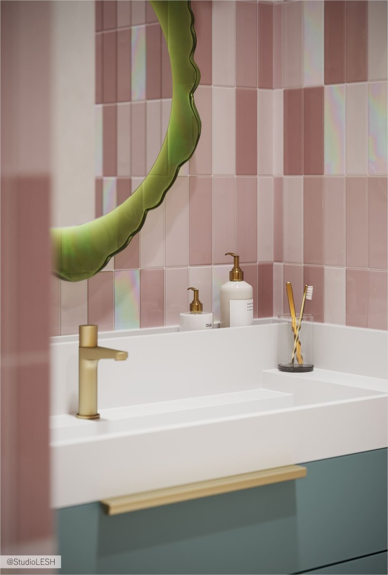 Современная ванная комната с розовой плиткой, зеркалом и золотым смесителем.
