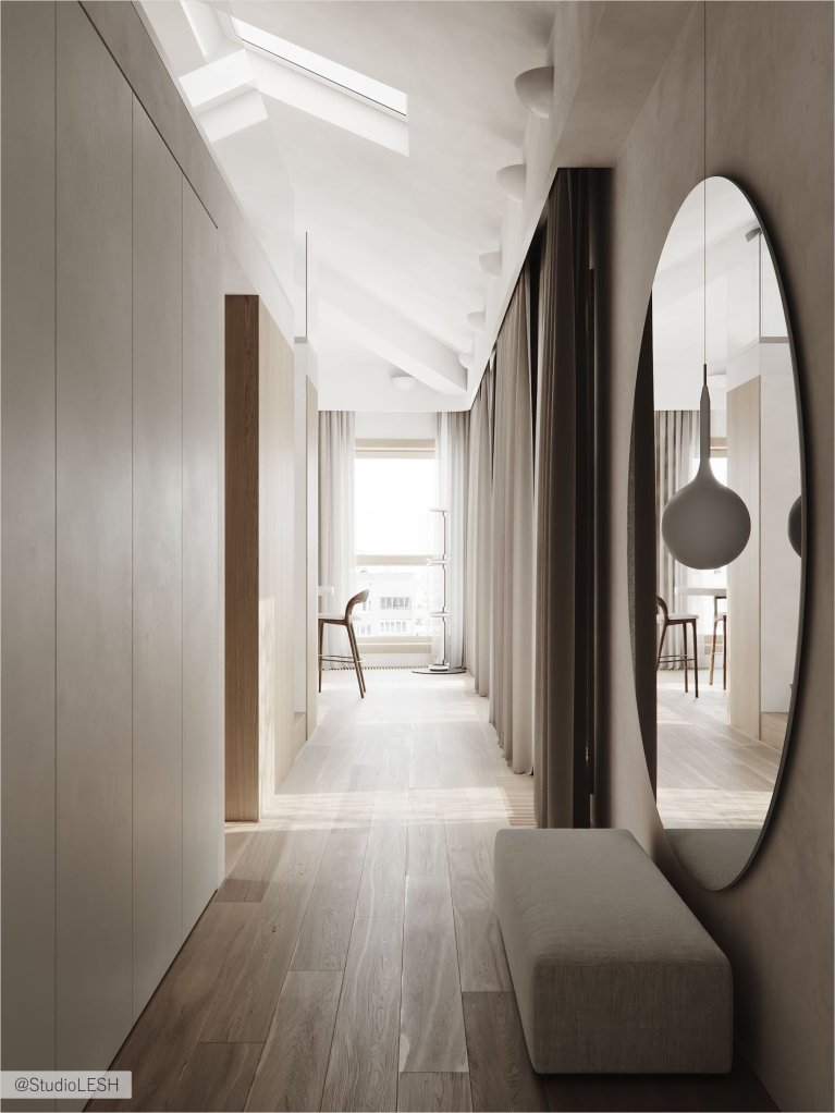 Интерьер современного коридора с белыми стенами, деревянным полом, встроенным шкафом с деревянными фасадами и большим круглым зеркалом.