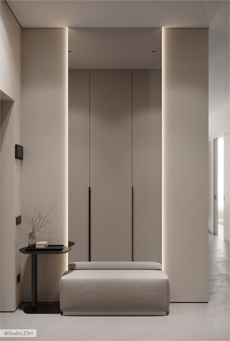 Интерьер современного коридора с белыми стенами, деревянным полом, встроенным шкафом с гладкими фасадами и мягкой скамьей.