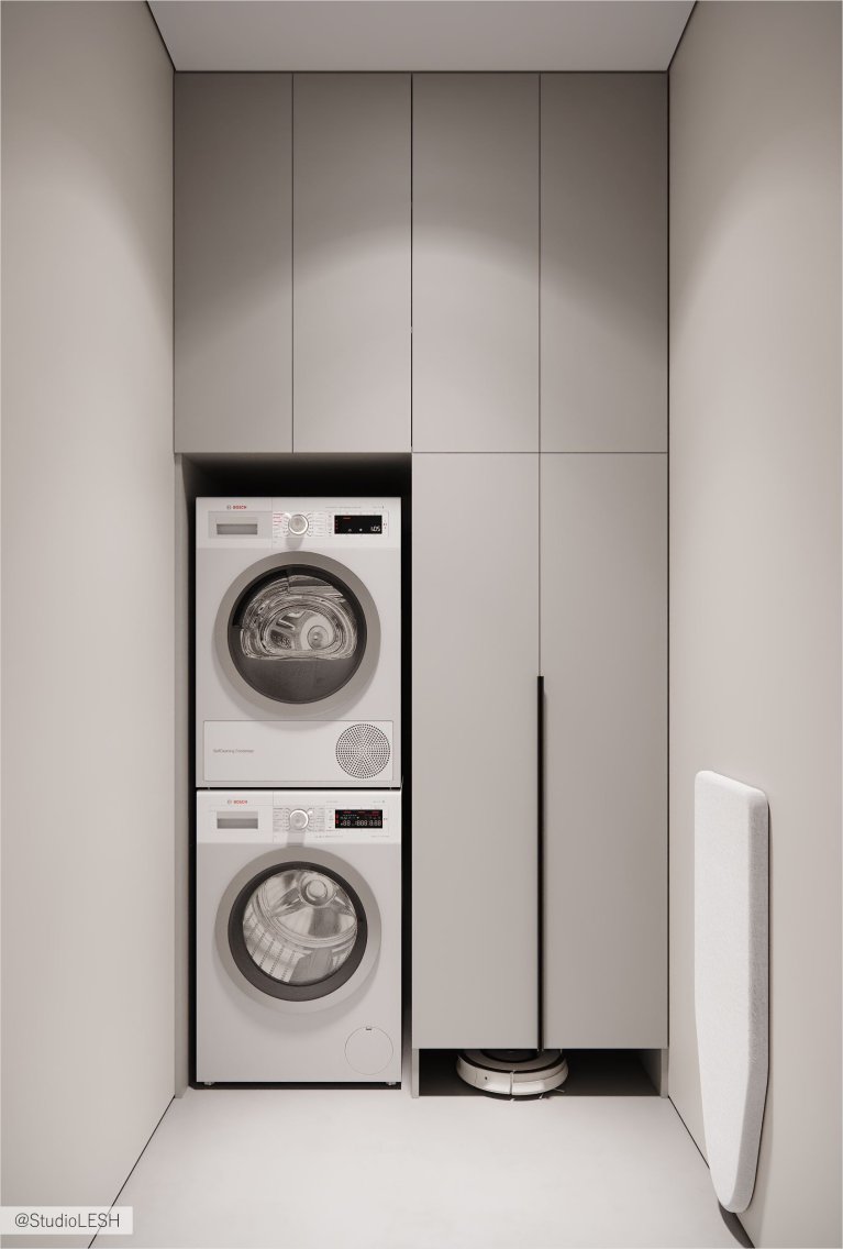 Современная прачечная с серыми шкафами и стиральными машинами.