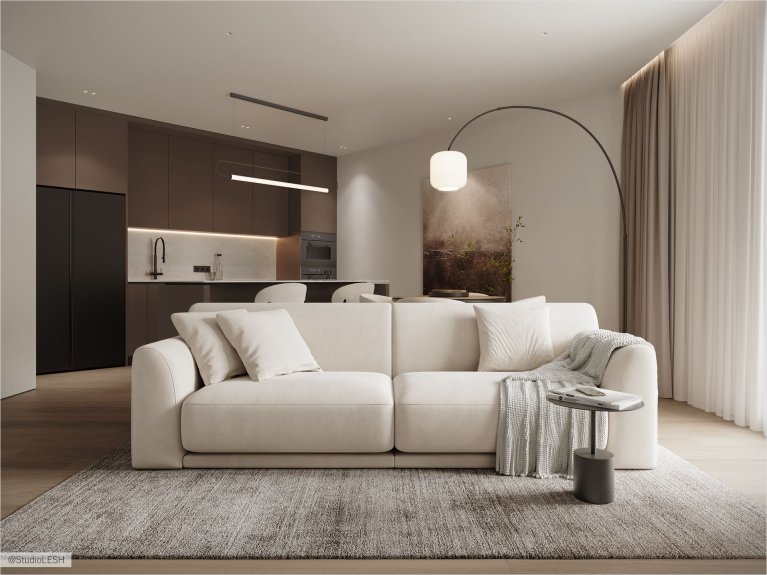 Современная кухня-гостиная в нейтральных оттенках с мягким бежевым диваном, минималистичной кухней с тёмными фасадами и подвесным освещением. Лаконичный дизайн с уютными деталями: пледом, декоративными подушками и журнальным столиком