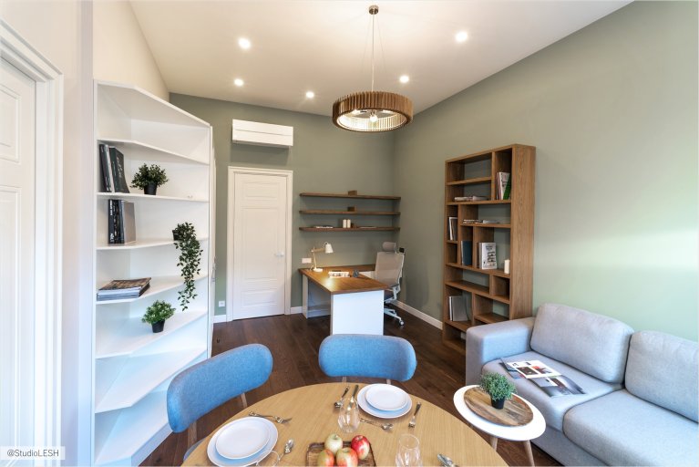 Светлая и просторная гостиная с большими окнами, паркетным полом и современной мебелью, создающая атмосферу комфорта и уюта