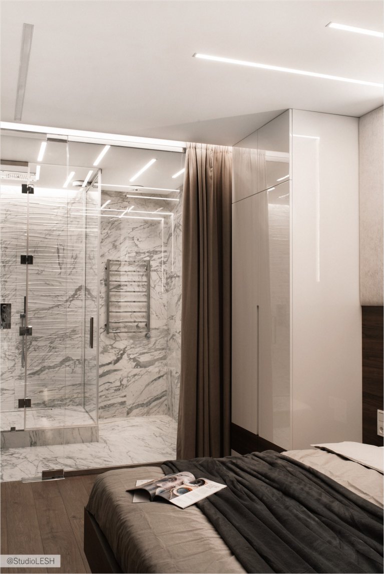 Дизайн современной спальни с душевой кабиной: стильный интерьер с большой кроватью и современным освещением.