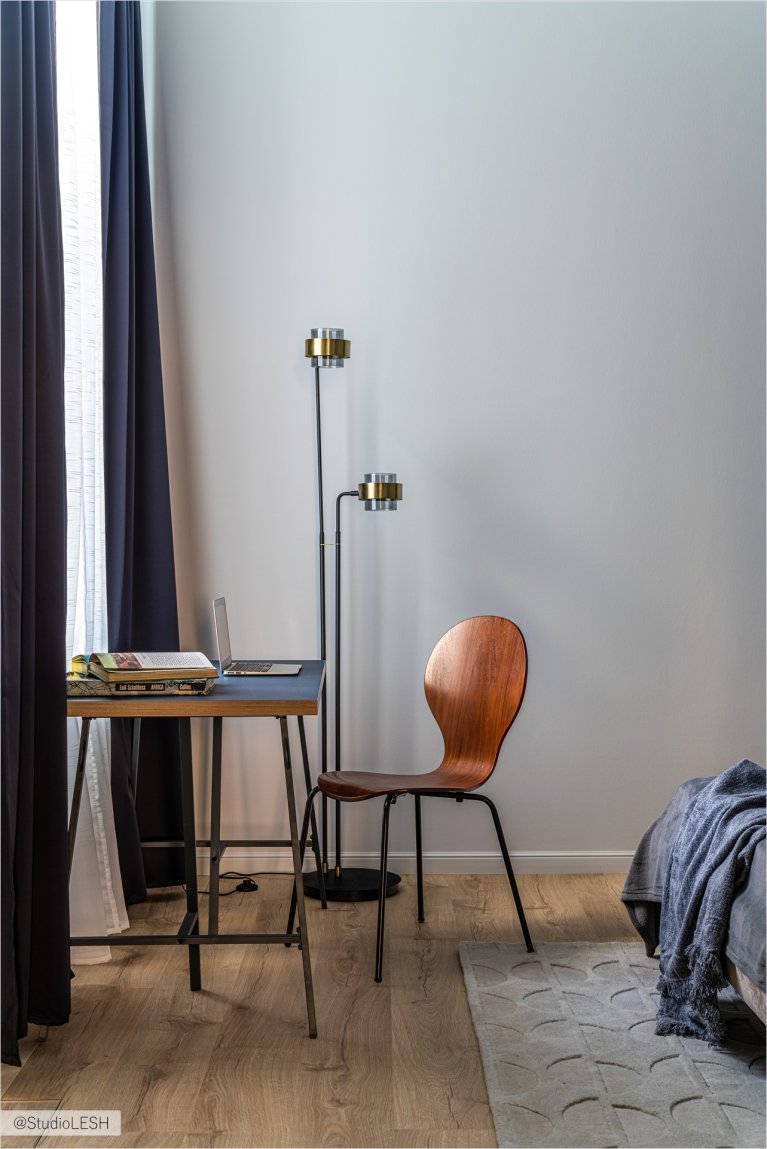 Удобный рабочий стол у окна с ноутбуком и настольной лампой, создающий комфортное рабочее пространство