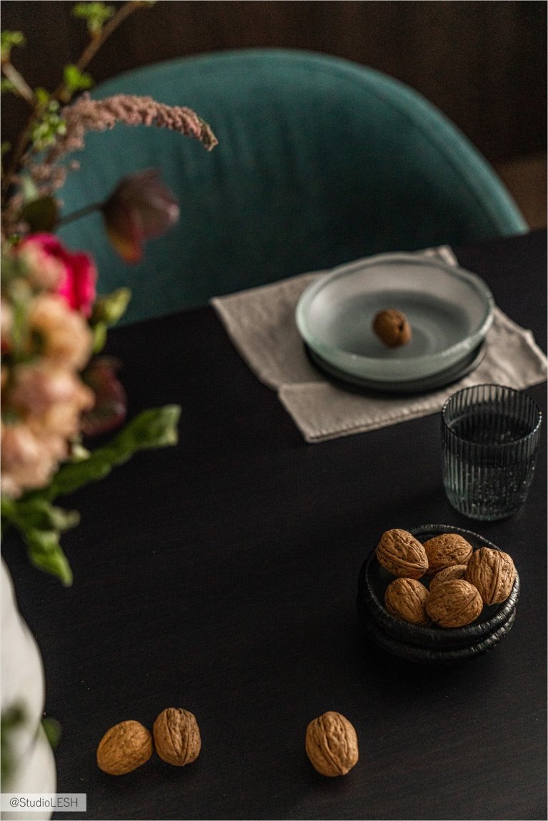 Сервировка стола: тёмная посуда с закусками и орехами на столе с чёрной столешницей
