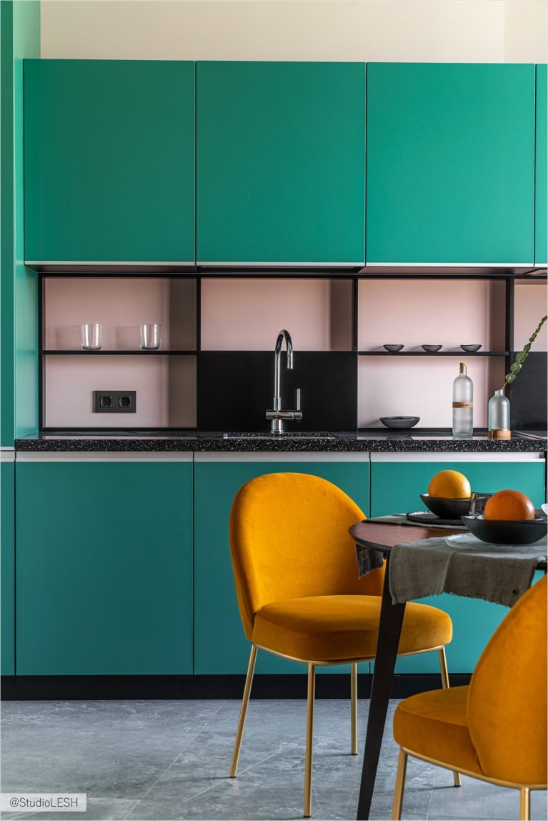 Интерьер современной кухни с яркими шкафами, обеденным столом на фоне окна и стильным декором