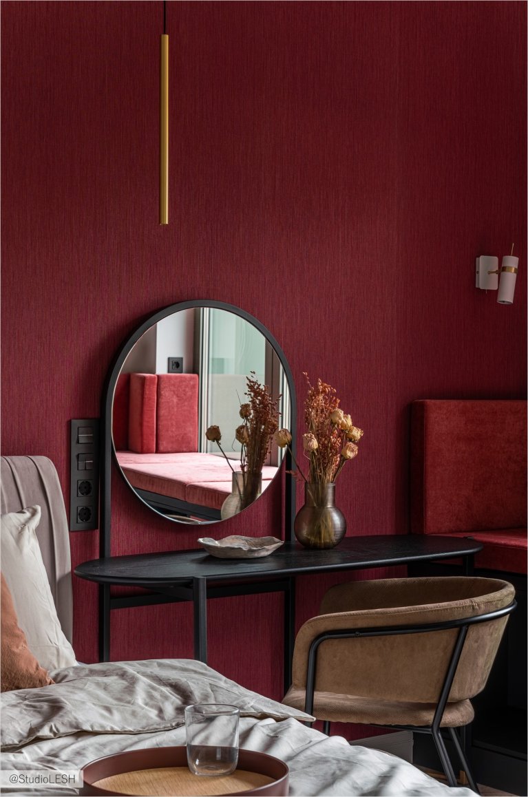 Спальня с большой кроватью с мягким изголовьем, на которой лежат декоративные подушки и покрывало