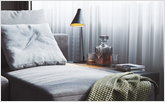 Серый светлый диван в кухне-гостиной с акцентным светом от настольной лампы для чтения